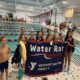 Group of Water Rats Swim Team participants holding up their banner after a swim meet