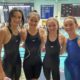 Competitive pre-teen swimmers at pool smiling
