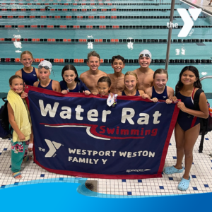 Swim team children holding banner by pool smiling