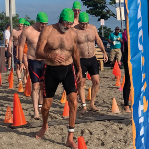 Swimmers cross the starting line to activate timers at Westport Weston YMCA 44th Point to Point at Compo Beach, Westport, CT.