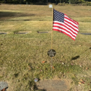 Volunteers installing durable flag holders on veterans' graves at Assumption Cemetery, showcasing community support and remembrance.