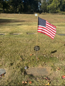 Volunteers installing durable flag holders on veterans' graves at Assumption Cemetery, showcasing community support and remembrance.